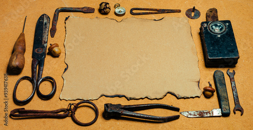 Rustic crafting background with vintage tools and a sheet of old paper on a wooden desk