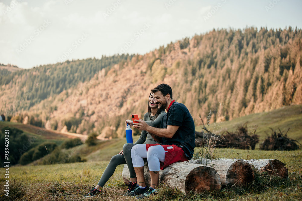 Sportswoman and sportsman sitting outdoors checking data on smartwatch and mobile Sportswoman and sportsman sitting outdoors checking data on smartwatch and mobile