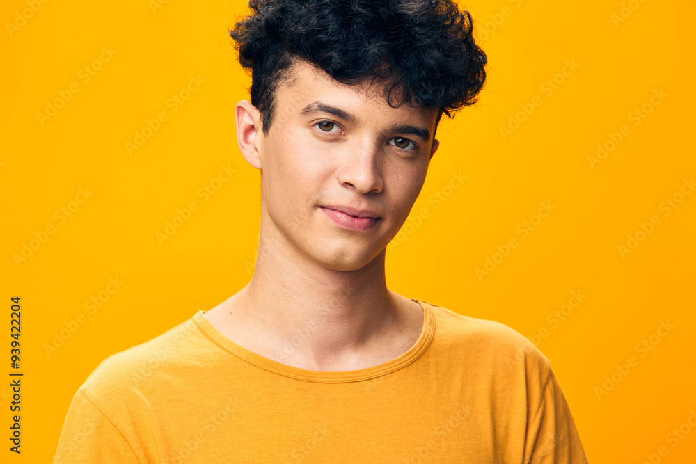 Portrait of a young man with curly hair wearing a yellow t shirt against a bright yellow background, conveying a cheerful and vibrant mood His expression is friendly and inviting Portrait of a young man with curly hair wearing a yellow t shirt against a bright yellow background, conveying a cheerful and vibrant mood His expression is friendly and inviting