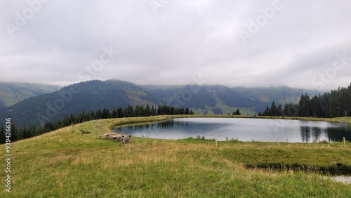 Alpine lake in the Austrian Alps. Forested mountains  and cloudy skies are in the background. 