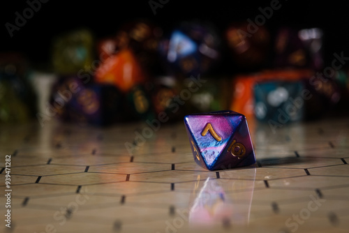 a blue and purple marbled eight-sided D8 dice with gold numbers, showing the number seven, sitting on a hexagonal tabletop gaming board with a variety of different types of dice in the background.  photo