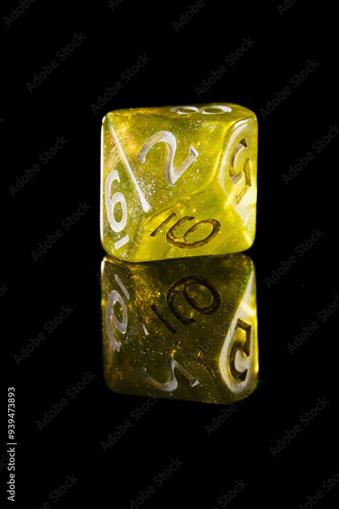 a translucent yellow ten-sided dice with white numbers, showing the number 4, on a black background with a reflection a translucent yellow ten-sided dice with white numbers, showing the number 4, on a black background with a reflection