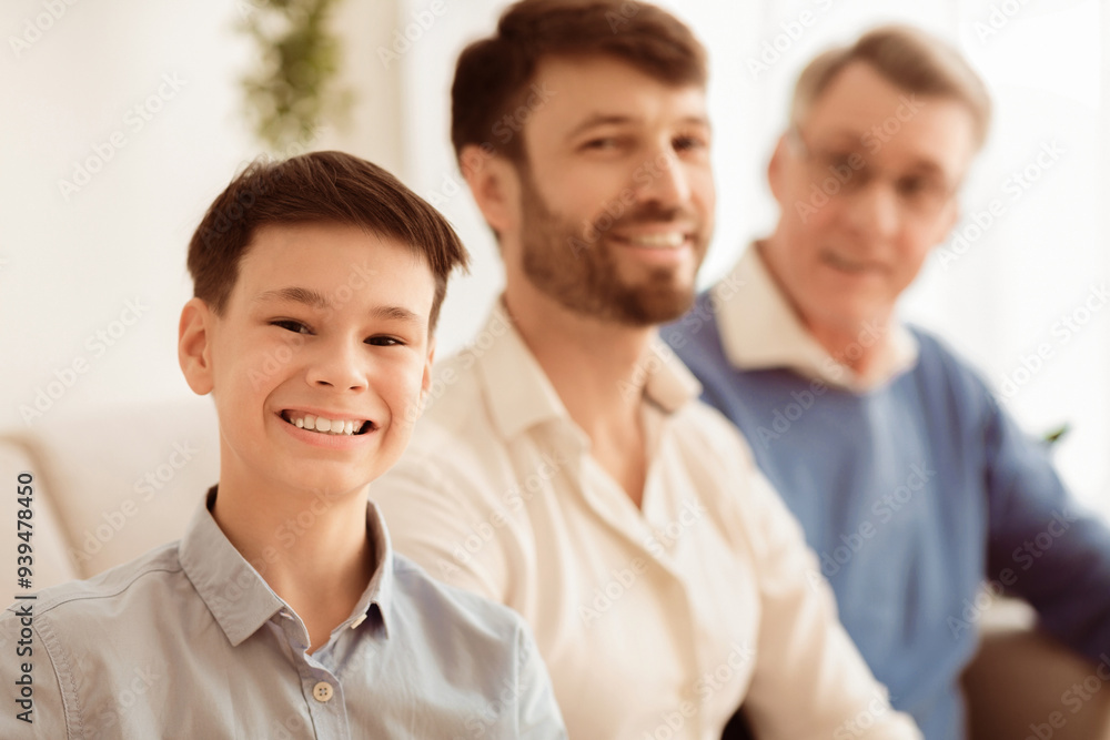Male Family. Cheerful Boy With Father And Grandfather Smiling At Camera Sitting On Couch At Home. Shallow Depth Male Family. Cheerful Boy With Father And Grandfather Smiling At Camera Sitting On Couch At Home. Shallow Depth