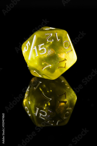 a translucent yellow twenty-sided dice with white numbers, showing the number fifteen, on a black background with a reflection