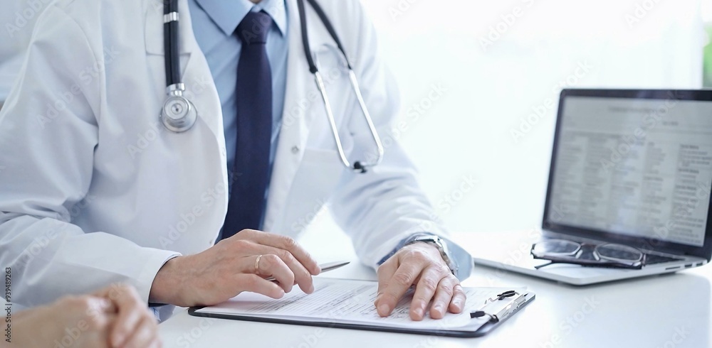 Doctor and a patient. The physician, wearing a white medical coat over a blue shirt and tie, gesturing with his hands during a consultation in the clinic. Medicine concept Doctor and a patient. The physician, wearing a white medical coat over a blue shirt and tie, gesturing with his hands during a consultation in the clinic. Medicine concept