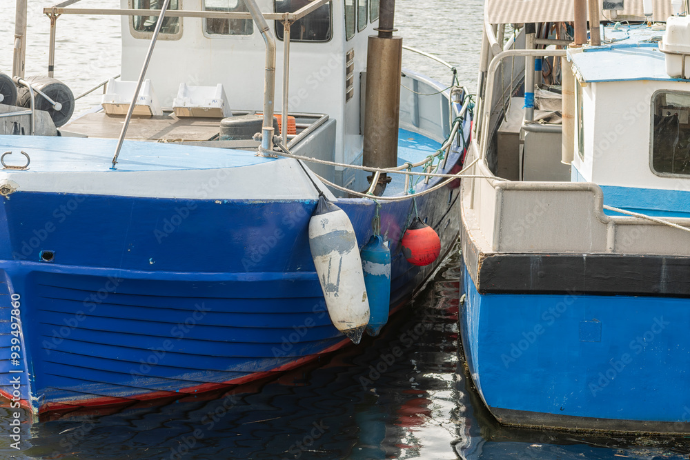 two fishing boats painted blue and white are moored next to each other two fishing boats painted blue and white are moored next to each other