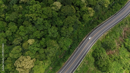 Aerial view of a road in the middle of the forest. Top view of asphalt road through forest with car adventure. Healthy environment road trip travel.
