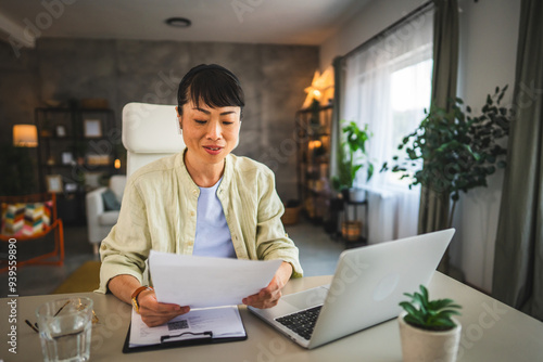 Mature japanese woman with earphones work from home on laptop