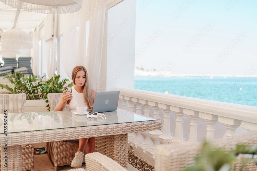 Woman coffee cafe laptop sea. Female freelancer using laptop on coffee break in modern cafe with sea view in the morning Woman coffee cafe laptop sea. Female freelancer using laptop on coffee break in modern cafe with sea view in the morning