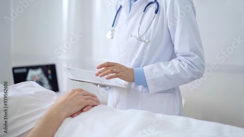 Doctor consulting patient with digital tablet in hospital room. Healthcare professional providing care