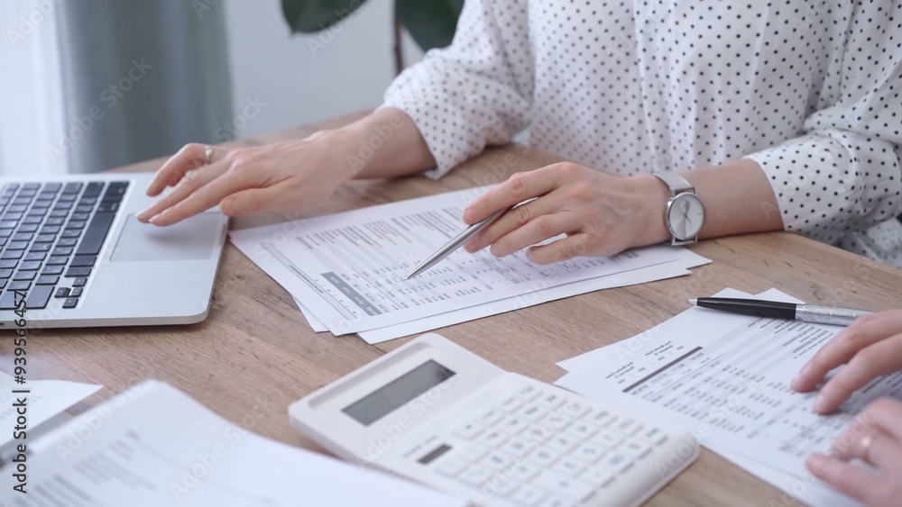 Fototapeta premium Bookkeeper woman is working with a colleague, using magnificent glass, calculator and laptop. Audit and taxes concept