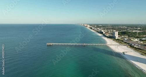Flying backwards above Panama City Beach pier, Gulf of Mexico, Florida. White sand beach in morning natural light