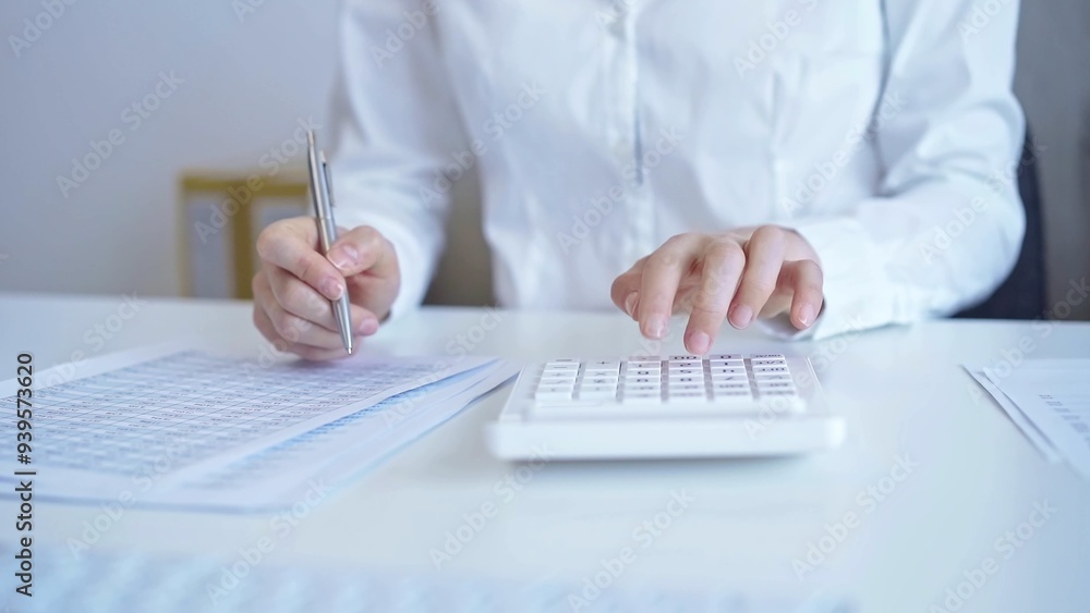 Fototapeta premium Businesswoman with white blues calculating finance with calculator and taking notes at office table. Audit and taxes