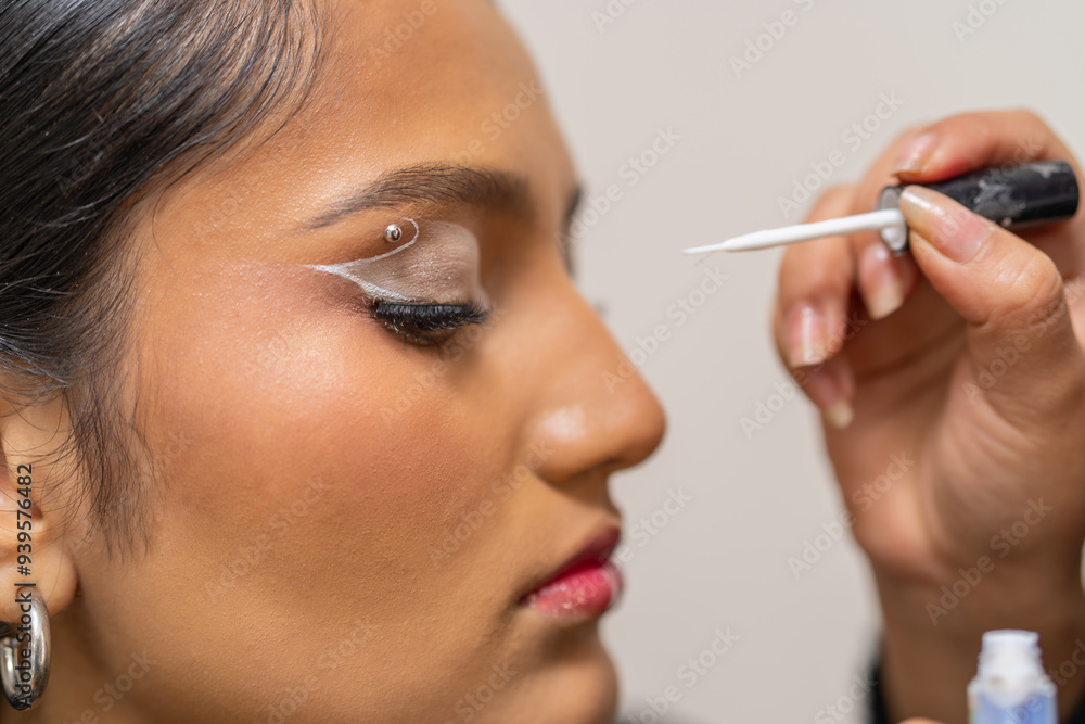 Make up artist applying white eyeliner to customer Make up artist applying white eyeliner to customer