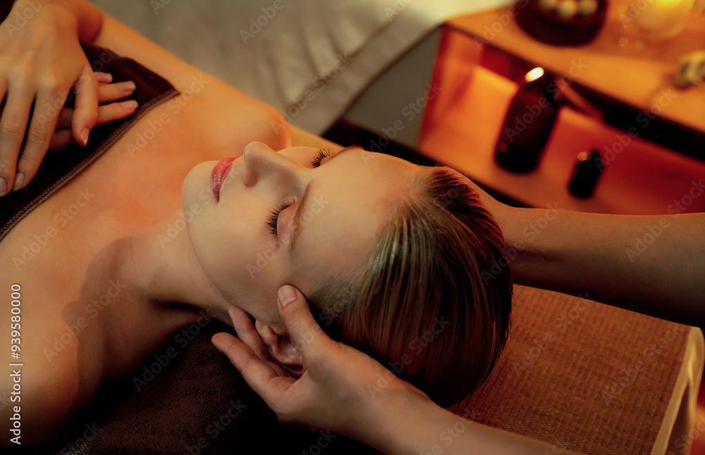 Obraz premium Caucasian woman enjoying relaxing anti-stress head massage and pampering facial beauty skin recreation leisure in warm candle lighting ambient salon spa in luxury resort or hotel. Quiescent