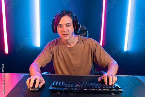 Host channel of gaming smart streamer playing online game to be winner, wearing headphone with viewers live steaming on media social online for selected team competition at neon light room. Pecuniary.