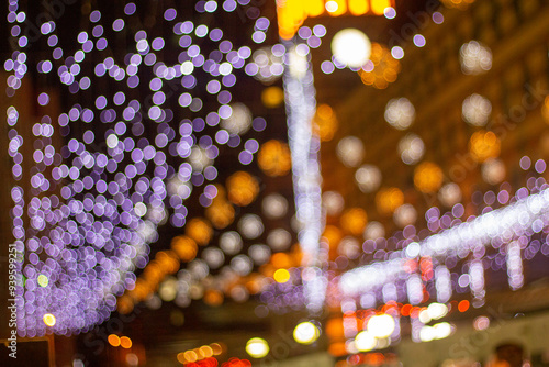 EncA mesmerizing display of festive bokeh lights fills the night sky, with hues of purple, white, and orange creating a magical ambiance. The city sparkles with holiday cheer and warmth.