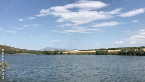 Wallpaper Mural Serene Lake Under a Bright Blue Sky with Soft White Clouds, Surrounded by Rolling Hills and Lush Farmland, Capturing the Peaceful Beauty of Nature on a Calm, Sunny Day in the Countryside Torontodigital.ca