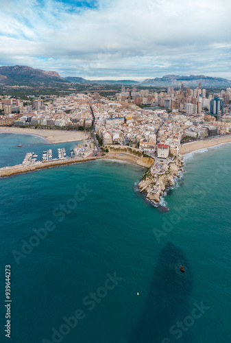 Aerial drone point of view of Benidorm city. Famous travel destination in Alicante province, Spain. Skyscrapers, mountains in background, Mediterranean Sea. Cloudy 