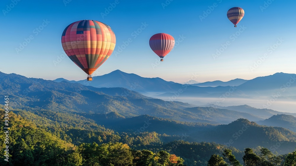 Naklejka premium Vibrant hot air balloons soar gracefully over the majestic mountain peaks of Dot Inthanon, casting an enchanting tapestry against the clear blue sky of Chiang Mai, Thailand. 