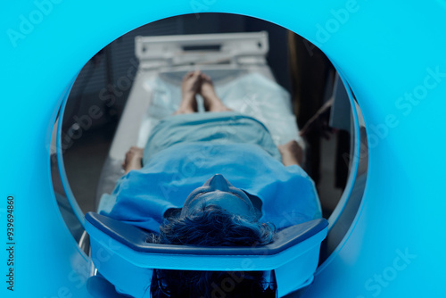 Patient lying in MRI machine for diagnostic scan, head first into tunnel, wearing medical gown for procedure photo