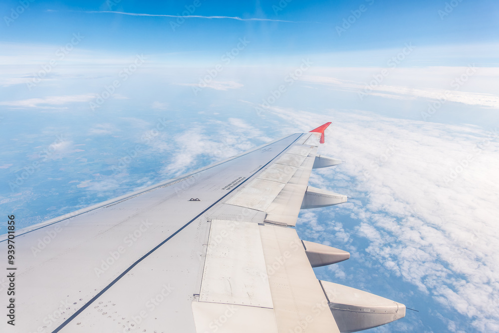 Fototapeta premium View from the airplane window at a beautiful cloudy sky and the airplane wing