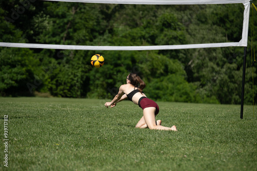 Volleyball player diving to pass the ball during a grass doubles game