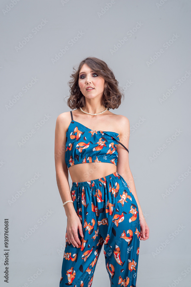 A woman with a beautiful figure in a blue top and blue pants with a fox pattern. She smiles and looks at the camera. A woman with a beautiful figure in a blue top and blue pants with a fox pattern. She smiles and looks at the camera.