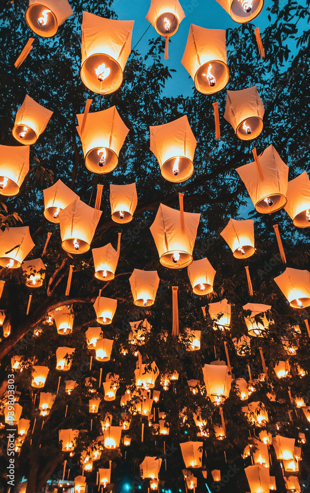 Naklejka premium Vibrant Traditional Lanterns Hanging Illuminated at Night with Intricate Designs, Cultural Decoration, Warm Glowing Lights in Air, Festival Atmosphere