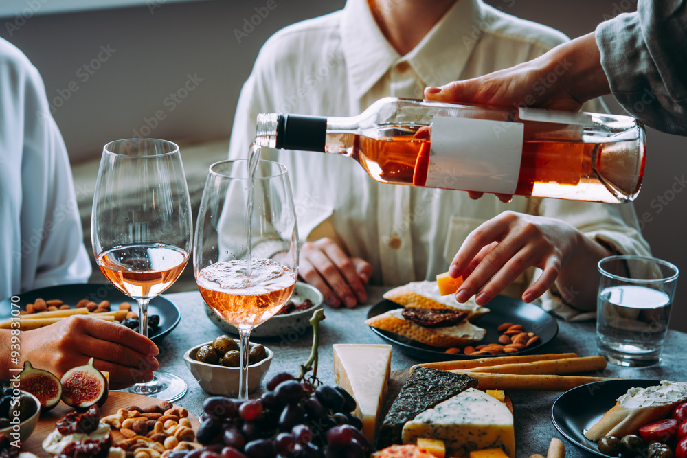 Pouring rose wine with classic snacks of cheese, bread and olives. Party or anniversary celebration.