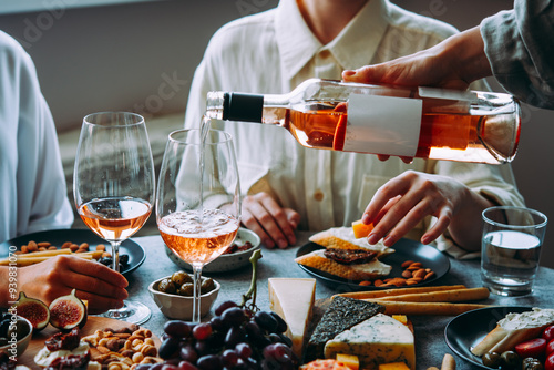 Obraz na płótnie Pouring rose wine with classic snacks of cheese, bread and olives. Party or anniversary celebration. w salonie