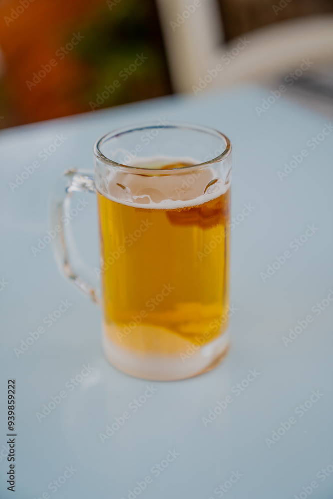 Tasty fresh beer glass on light blue table background in Greece for vacation and having refreshing drink