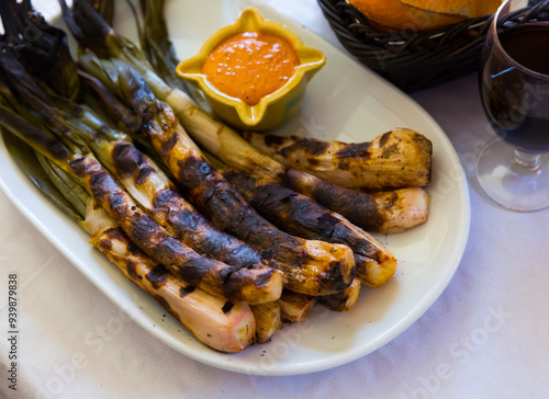 Traditional Catalan Calcotada dish served in restaurant - calcots roasted over open fire with romesco sauce and red wine photo