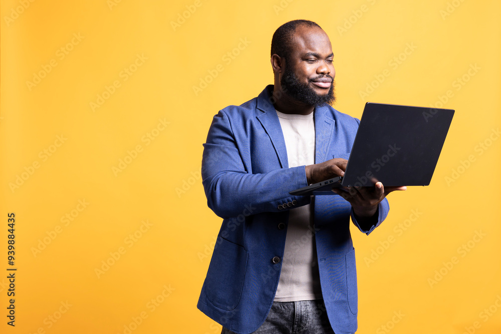 Smiling african american man looking at business diagram and figures on laptop, isolated over studio background. Upbeat worker checking company financial annual report charts on notebook Smiling african american man looking at business diagram and figures on laptop, isolated over studio background. Upbeat worker checking company financial annual report charts on notebook