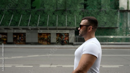 Muscular man standing still on city street.