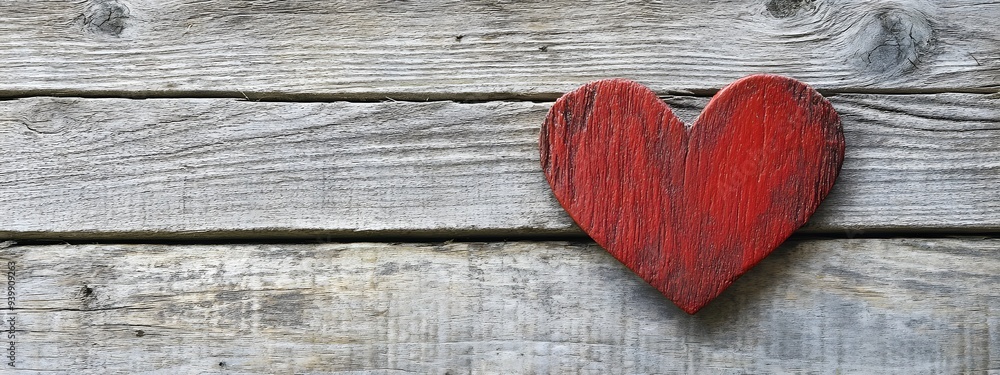 A red heart on an old wooden background symbolizes love and affection for a Valentine's Day celebration A red heart on an old wooden background symbolizes love and affection for a Valentine's Day celebration