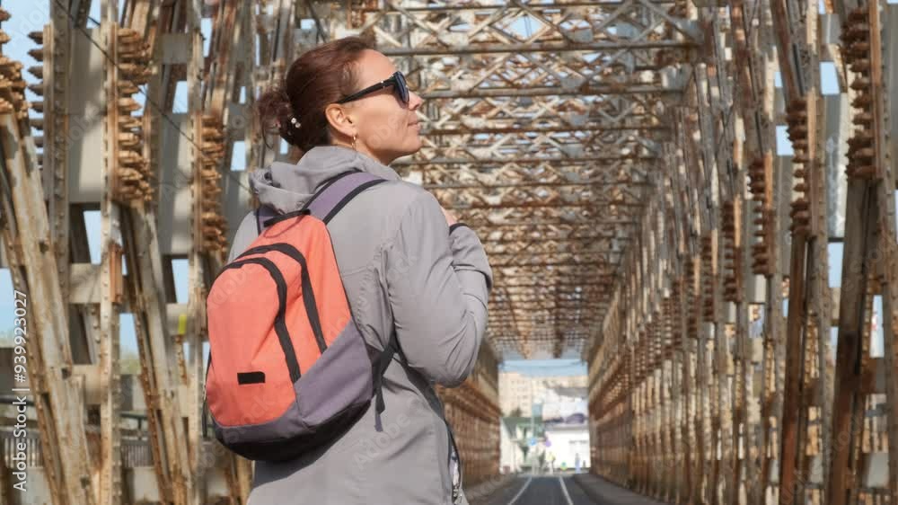 Traveler with backpack on rusty bridge. A woman traveler with backpack walk along the rusty bridge and admire the construction. Traveler with backpack on rusty bridge. A woman traveler with backpack walk along the rusty bridge and admire the construction.
