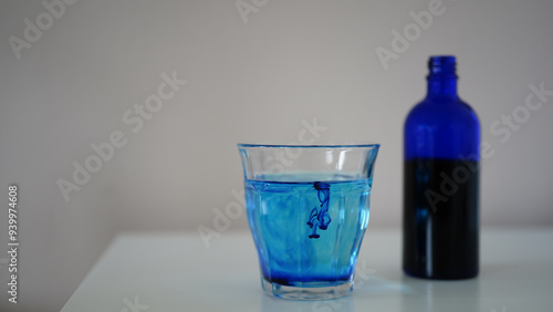 image showing a bottle filled with methylene blue near a glass with water and methylene blue.