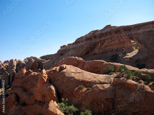 Hiking to famous Partition Arch, two round holes in massive red rock, Arches National Park, Utah