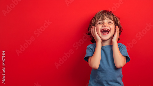 un niño muy contento sonriendo y riendo feliz y alegre con sus emociones de felicidad lindo niño rubio modelando sobre un fondo rojo con espacio para copiar photo