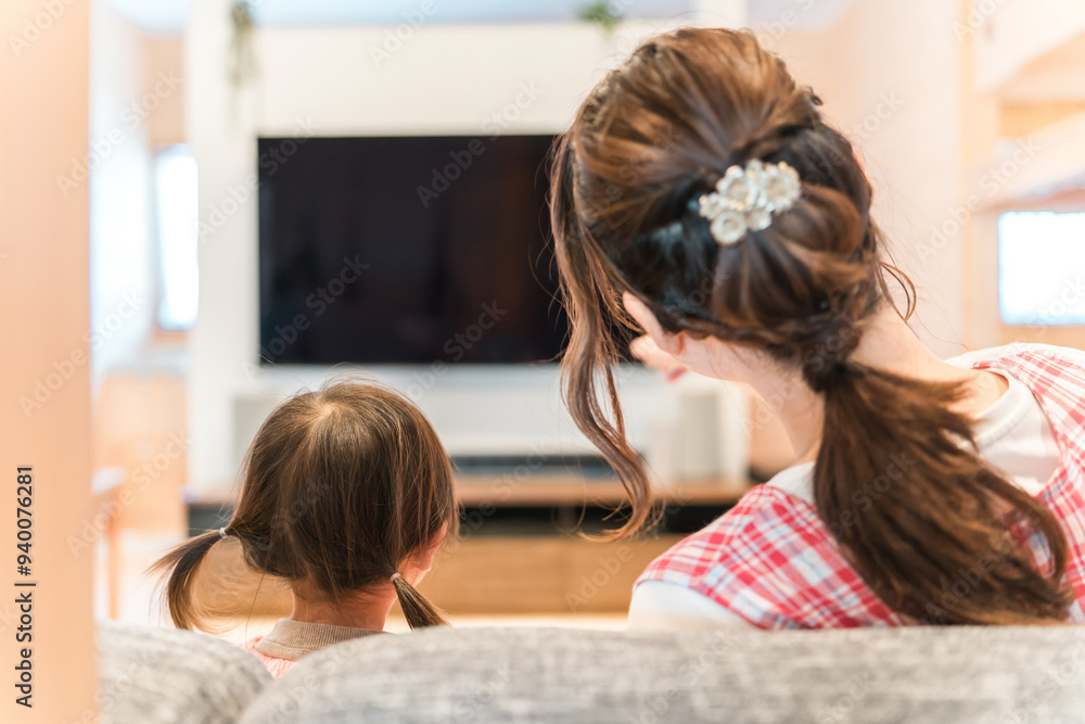 Fototapeta premium 保育園・幼稚園・託児所・保育所でテレビを見る女の子と保育士・ベビーシッターの女性