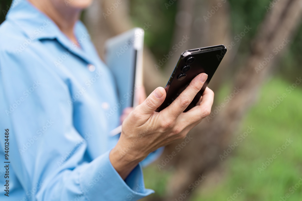 Business Professional Using Smartphone and Tablet Outdoors in a Natural Setting Business Professional Using Smartphone and Tablet Outdoors in a Natural Setting