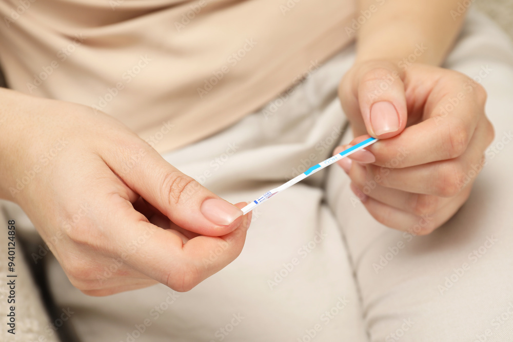 Woman holding pregnancy test indoors, closeup view Woman holding pregnancy test indoors, closeup view