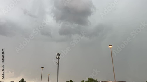 Lighting strikes in the background behind a cellular tower during a thunderstorm - storm clouds loom in the distance as a storm moves through a midwestern urban area photo