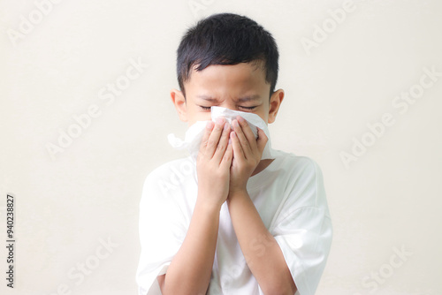 Little asian boy sick and sad with sneezing on nose and cold cough on tissue paper becauseweak or virus and bacteria. cold allergies or illness, health, photo