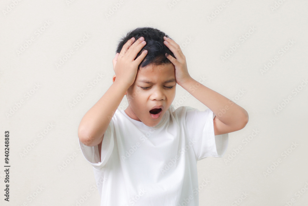 Frustrated little asian boy suffers from headache, keeps hands on temples, isolated on white background. Frustrated little asian boy suffers from headache, keeps hands on temples, isolated on white background.