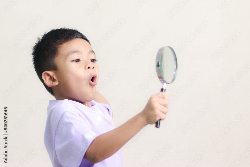 Portrait of surprised cute little asian boy looking through a magnifying glass. Education concept. Portrait of surprised cute little asian boy looking through a magnifying glass. Education concept.
