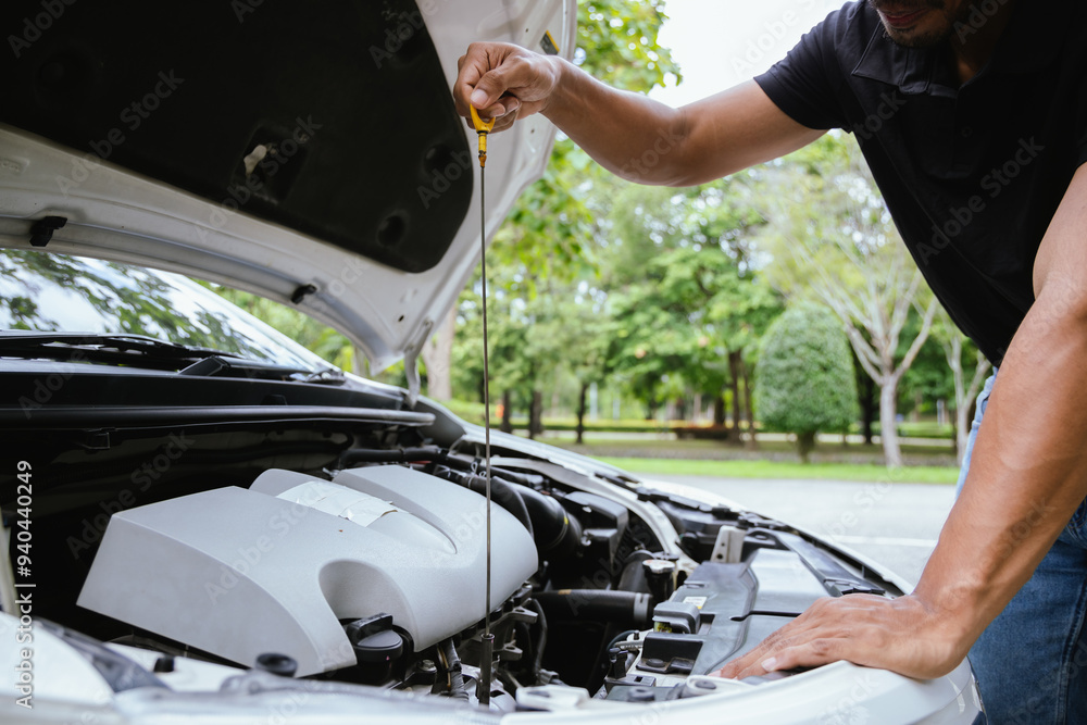 A technician in a Thailand auto repair shop conducts diagnostics on a car engine using a laptop. The scene highlights advanced technology in automotive inspection and repair. A technician in a Thailand auto repair shop conducts diagnostics on a car engine using a laptop. The scene highlights advanced technology in automotive inspection and repair.