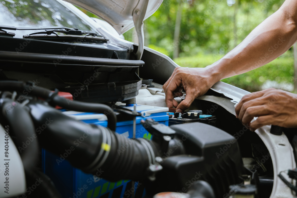 A technician in a Thailand auto repair shop conducts diagnostics on a car engine using a laptop. The scene highlights advanced technology in automotive inspection and repair. A technician in a Thailand auto repair shop conducts diagnostics on a car engine using a laptop. The scene highlights advanced technology in automotive inspection and repair.