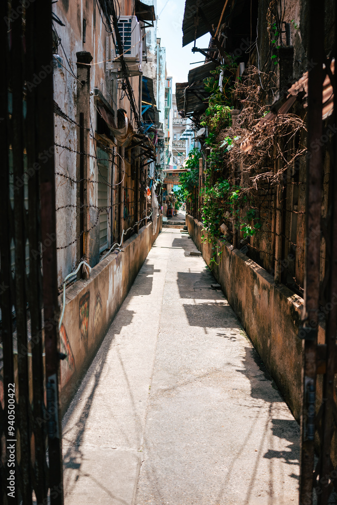Fototapeta premium View of an urban alleyway with vibrant graffiti and barbed wire. The image captures a gritty yet colorful representation of city life and urban decay.